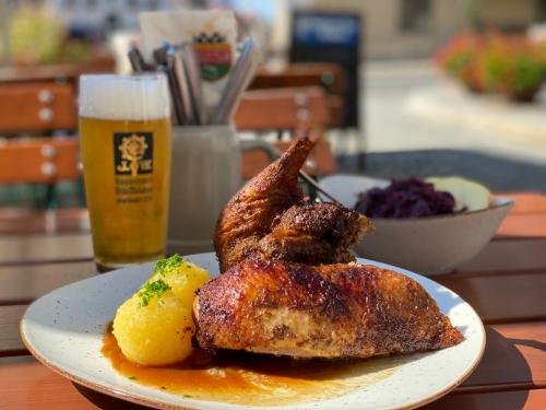 a plate of chicken and potatoes and a glass of beer at HHotel Augsburg in Augsburg