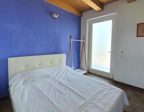 1 dormitorio con cama blanca y pared azul en Cascina la Demilana en Bibiana