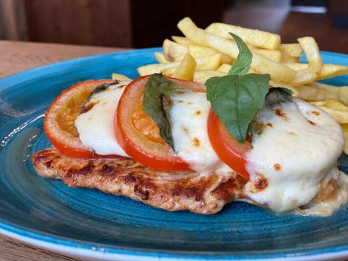 a blue plate with a piece of meat with tomatoes and french fries at HHotel Augsburg in Augsburg
