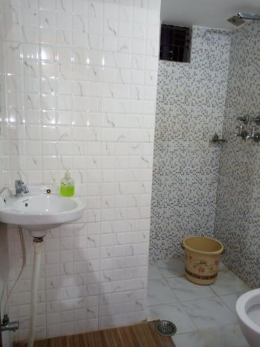 a white bathroom with a sink and a shower at Bliss Guest House Assi Ghat in Varanasi