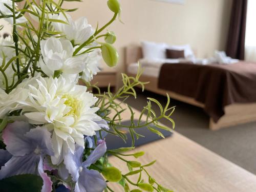 a vase of white flowers on a table in a room at VILARHOTEL in Aizkraukle