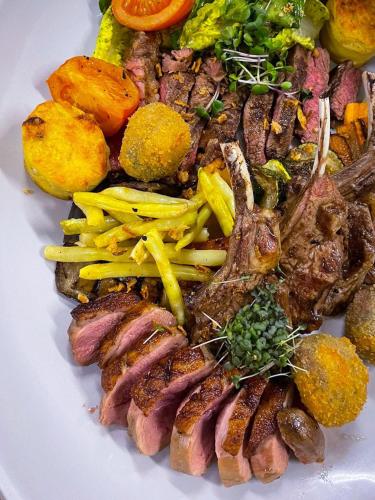 a white plate of food with meat and vegetables at VILARHOTEL in Aizkraukle