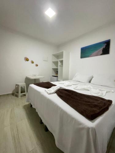 a large bed in a white room with a table at Maragobeach Suits in Maragogi