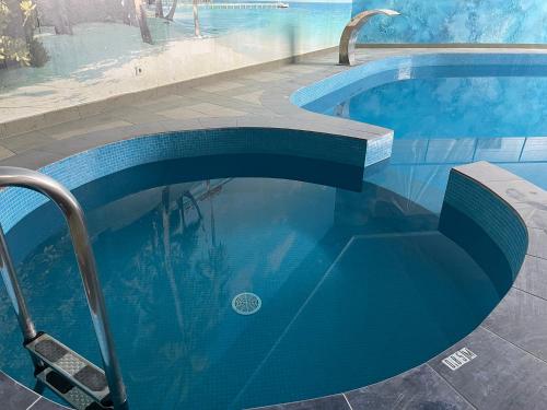 a blue swimming pool with a bench in it at VILARHOTEL in Aizkraukle