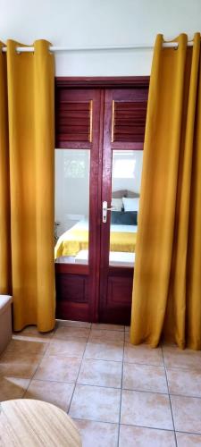 a bedroom with yellow curtains in front of a bed at Bungalow et Duplex de Island Bay in Bouillante
