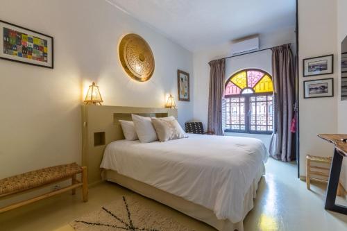 ein Schlafzimmer mit einem weißen Bett und einem Fenster in der Unterkunft "LE 21", EXCLUSIVE LUXURY DUPLEX 400m FROM JEMAA EL FNA PLACE -HAMMAM-JACUZZI-KOUTOUBIA VIEW-ROOF TERRACE -SPEED WIFI in Marrakesch