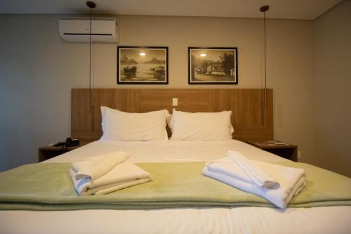 a bedroom with a bed with two towels on it at WINNER BEACH HOTEL in Juréia