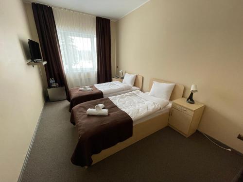 two beds in a hotel room with towels on them at VILARHOTEL in Aizkraukle