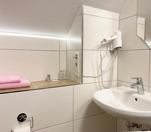 a white bathroom with a sink and a phone at Bauer´s Pension-Restaurant-Catering in Großhabersdorf