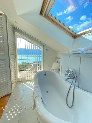 ein Bad mit einer Badewanne und einem großen Fenster in der Unterkunft Villa Zenitude in Veyrier-du-Lac