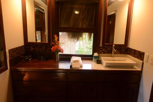 a bathroom counter with a sink and a mirror at El Ben Cabañas in Caye Caulker