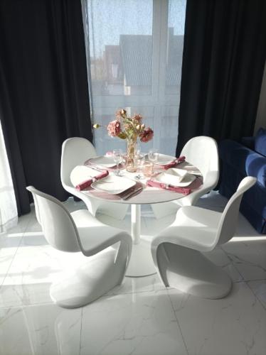 une table blanche avec des chaises blanches et un vase de fleurs dans l'établissement Apartament Słoneczny, à Dziwnówek