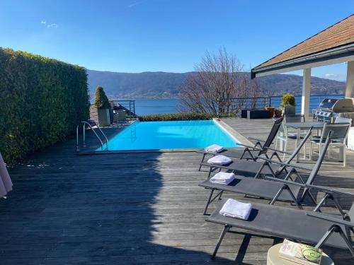 une piscine avec des chaises longues à côté d'une maison dans l'établissement Villa Zenitude, à Veyrier-du-Lac
