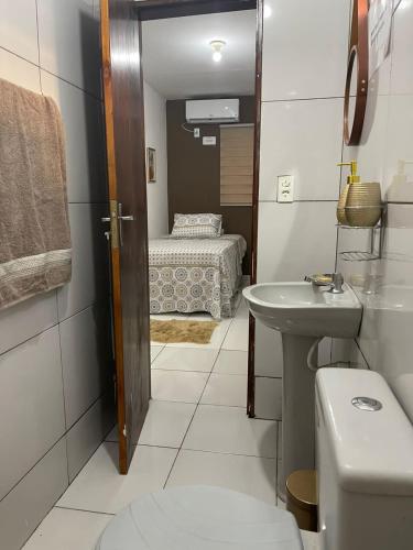 a bathroom with a sink and a toilet and a bed at Flat JK 202 in Juazeiro do Norte