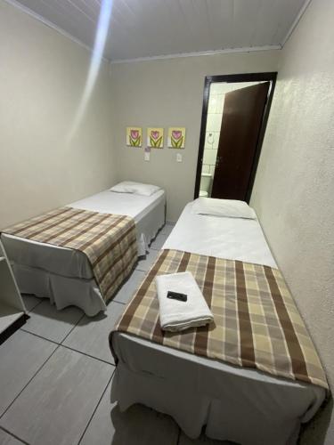 a room with two beds and a mirror at Hotel Zata - Econômico in Criciúma