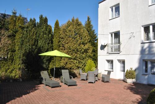 un patio con sillas y una sombrilla junto a un edificio en Pokoje gościnne Simon, en Mielno