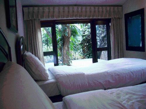 a bedroom with two beds and a window with a view at Momchailai Pattaya Retreat in Pattaya South