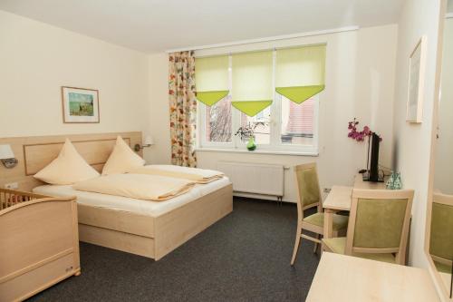 a bedroom with a bed and a table and a desk at Landhotel Bad Dürrenberg in Bad Dürrenberg