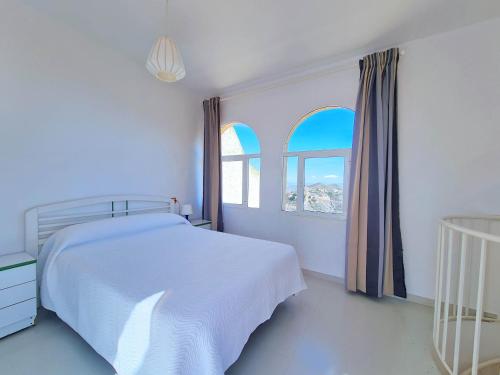 a white bedroom with a bed and two windows at Catalejo chalet casa rural 18 plazas in Águilas