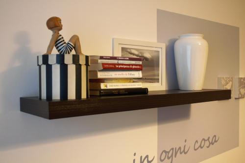 a shelf with a stack of books and a vase at Appartamento Liberazione - 5 Terre Region in Moneglia