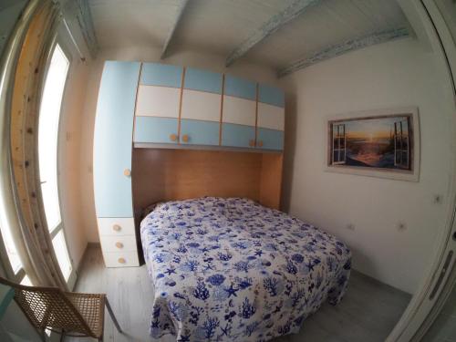 a bedroom with a bed with a blue and white blanket at Perla del mare in Calasetta