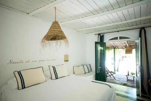 1 dormitorio con cama blanca y lámpara de araña en Posada Paradiso en José Ignacio