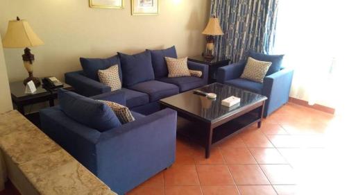 a living room with blue couches and a coffee table at Patio suite, Porto marina in El Alamein