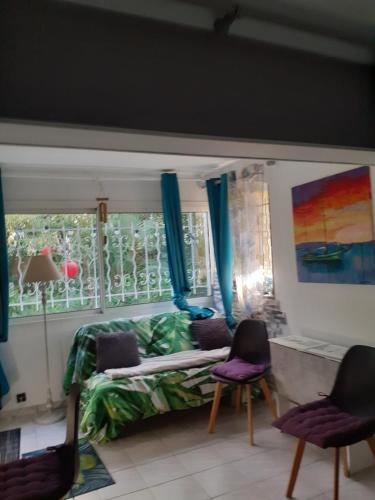 Habitación con cama, 2 sillas y ventana en Jardin et bambous, studio cosy, classé 2 étoiles, en Marseillan