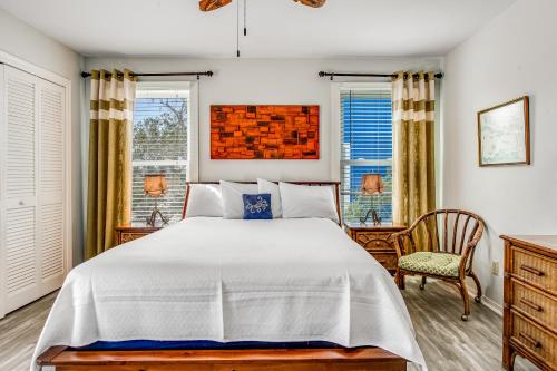 a bedroom with a bed and a chair and windows at The Flip Side by Meyer Vacation Rentals in Gulf Shores