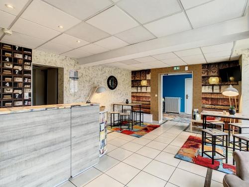 a lobby with a bar and tables and chairs at Logis Hotel Beaudon in Pierrefonds