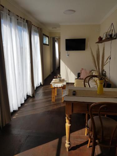 sala de estar con cortinas blancas y mesa en Ollagua Tiny House Sierra de la Ventana en Tornquist