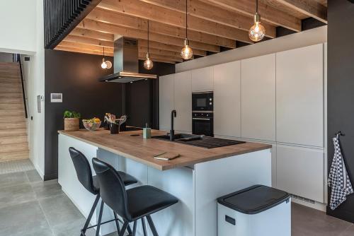 a kitchen with white cabinets and a counter with stools at In't Groene Woud in Peer
