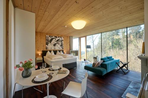 a room with a bed and a couch and a table at Design Apartment mit Panoramafenster & Naturblick - KLIMATISIERT in Bregenz