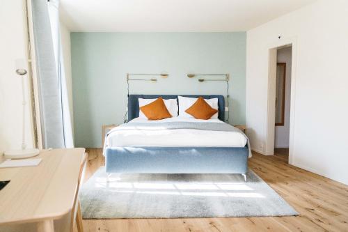 a bedroom with a blue bed with orange pillows at Hemma in Aubonne