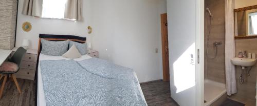a bedroom with a bed with a blue comforter and a sink at House LA Neuschwanstein Blick - Budget City Hotel in Füssen