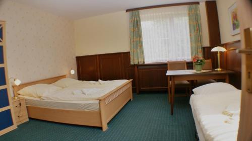 a hotel room with two beds and a desk at Gasthaus & Hotel Lindenkrug in Poseritz