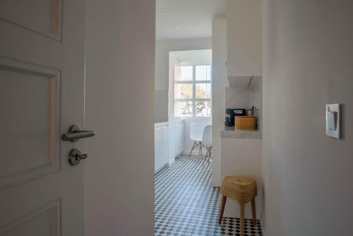 a hallway with a door and a kitchen with a stool at Inesquecível estadia na praia de Carcavelos in Carcavelos