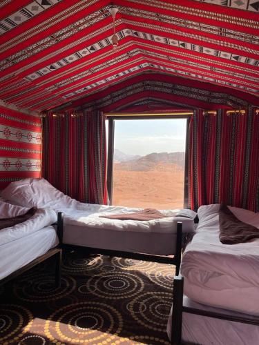 a room with two beds and a window with a desert at Wadi Rum Starlight Camp in Wadi Rum
