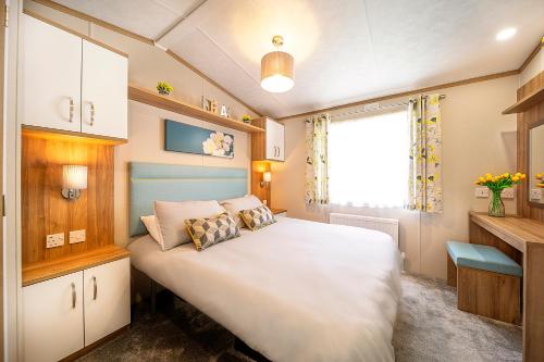 een slaapkamer met een groot wit bed en een raam bij Discover, Relax, Enjoy - All-Round Luxury Lodge in Carlisle