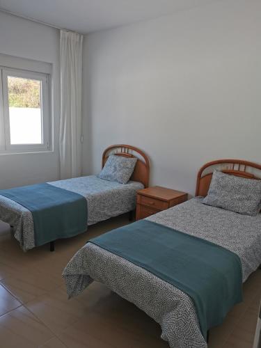a bedroom with two beds and a window at Apartamento O Serrano in Finisterre