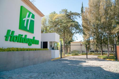 a sign for a hotel in front of a gate at Holiday Inn Tlaxcala by IHG in Tlaxcala de Xicohténcatl
