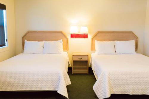 a hotel room with two beds with white sheets at Two Sunsets Hotel in Panguitch