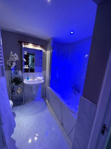 a bathroom with a tub and a sink and blue lighting at Gleneagles Lettings in Auchterarder