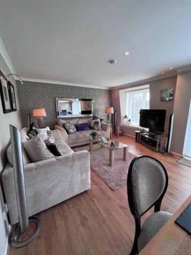 a living room with a couch and a television at Gleneagles Lettings in Auchterarder