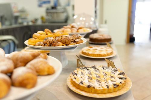 a table with different types of pastries on plates at Hotel Edelweiss Riccione in Riccione