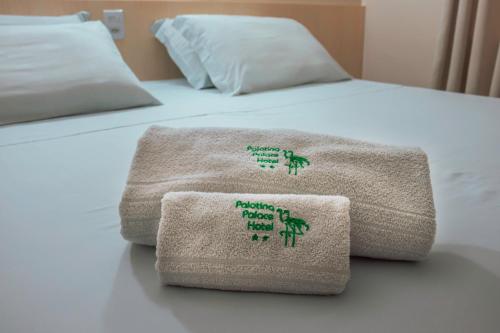 a bed with two towels sitting on top of it at Palotina Palace Hotel in Palotina