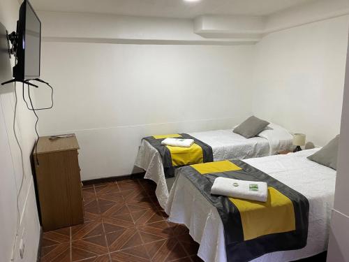 a room with two beds and a television in it at Hostal CECIL + in Vallenar
