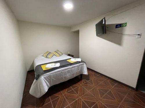 Habitación pequeña con cama y TV. en Hostal CECIL + en Vallenar