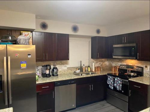 a kitchen with brown cabinets and a stainless steel refrigerator at Sweet dreams private room across from the Hard Rock Casino in Tampa