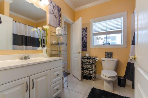 a bathroom with a toilet and a sink and a window at Five O'clock Somewhere 4Bd By Pkrm in Pensacola